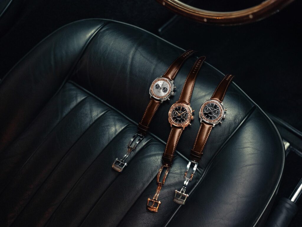 Colección de tres relojes Breitling Top Time B01 Chronograph 41 Tribute to Aston Martin DB5 sobre el asiento de cuero del coche.