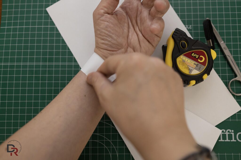 Medición de la circunferencia de la muñeca con cinta métrica flexible de costura para elegir talla de correa de reloj.