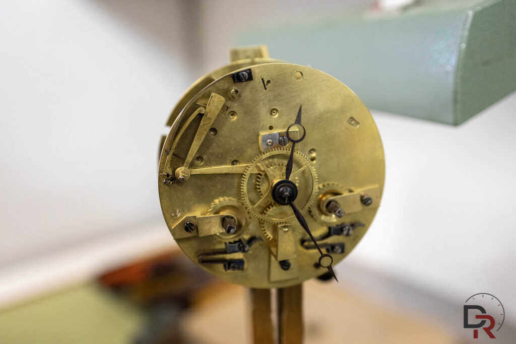 Dismantling and bronze dial of an antique horological movement on the workbench