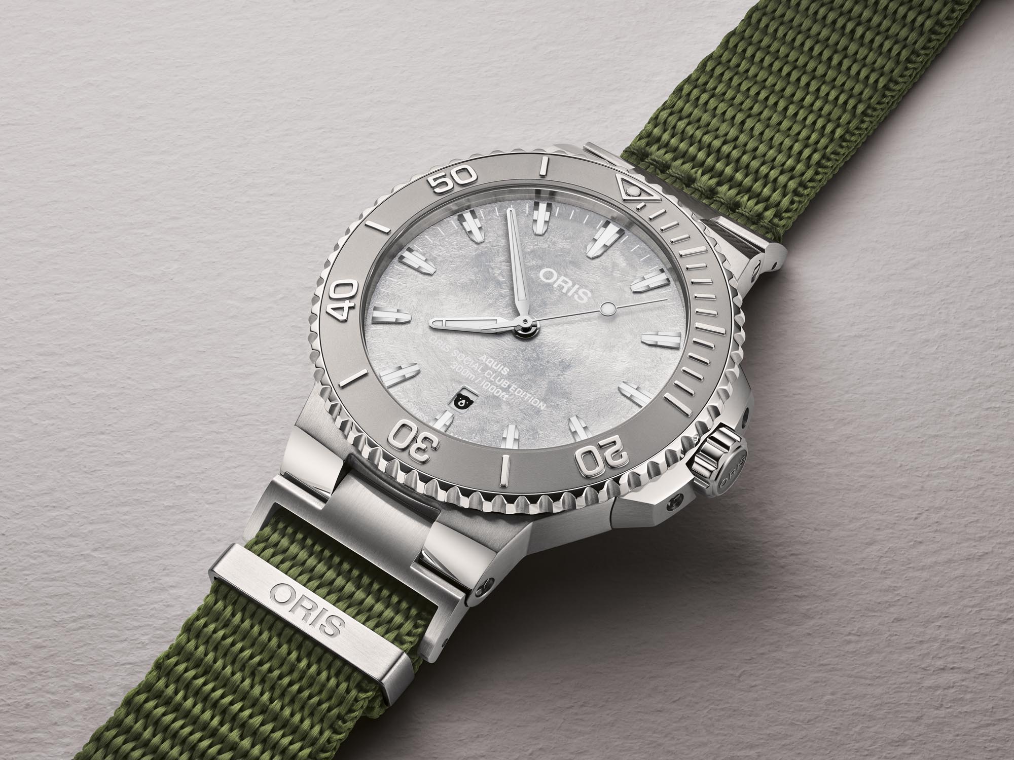 Reloj Oris Social Club Edition II Aquis Date Relief con esfera frosted silver y correa NATO verde